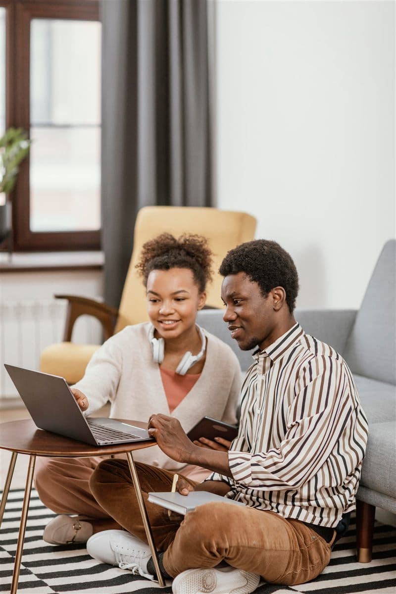 Two students smiling while looking at a laptop together