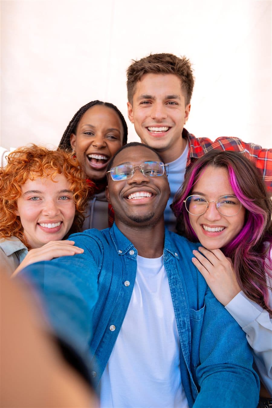 A group of five smiling young adults posing for a selfie