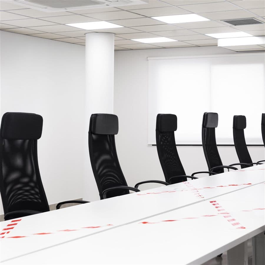 A modern, empty meeting room with a long white table and black chairs