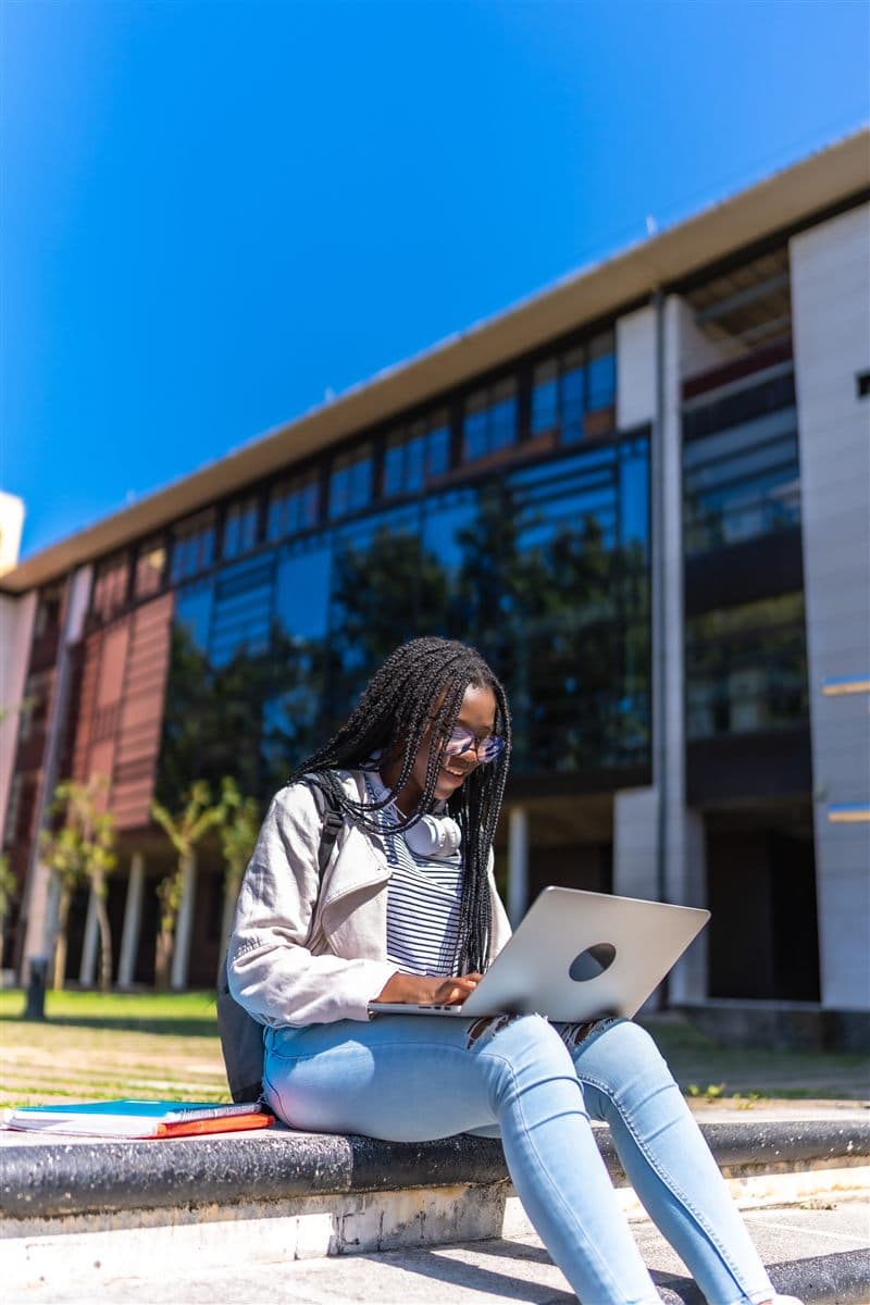 Student working on a laptop outdoors on a university campus