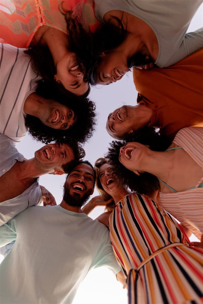 Group of students in a huddle looking down at the camera